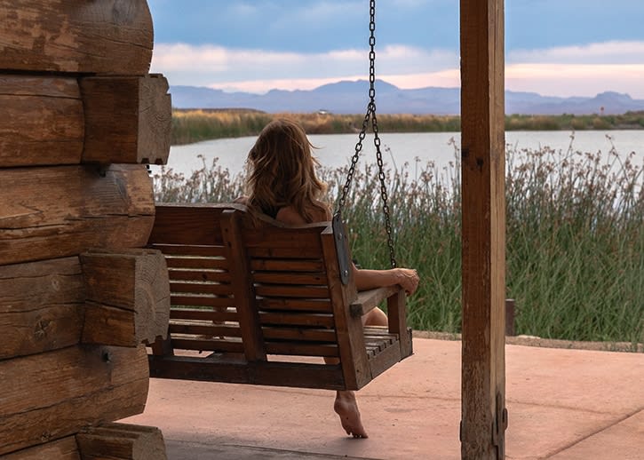 A woman sitting on a porch swing watching a sunset storm at Roper Lake State Park, from the deck of the Hummingbird Cabin