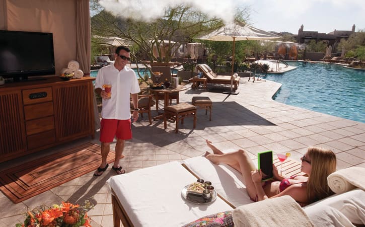 A man and woman relax in a private luxury cabana near a pool