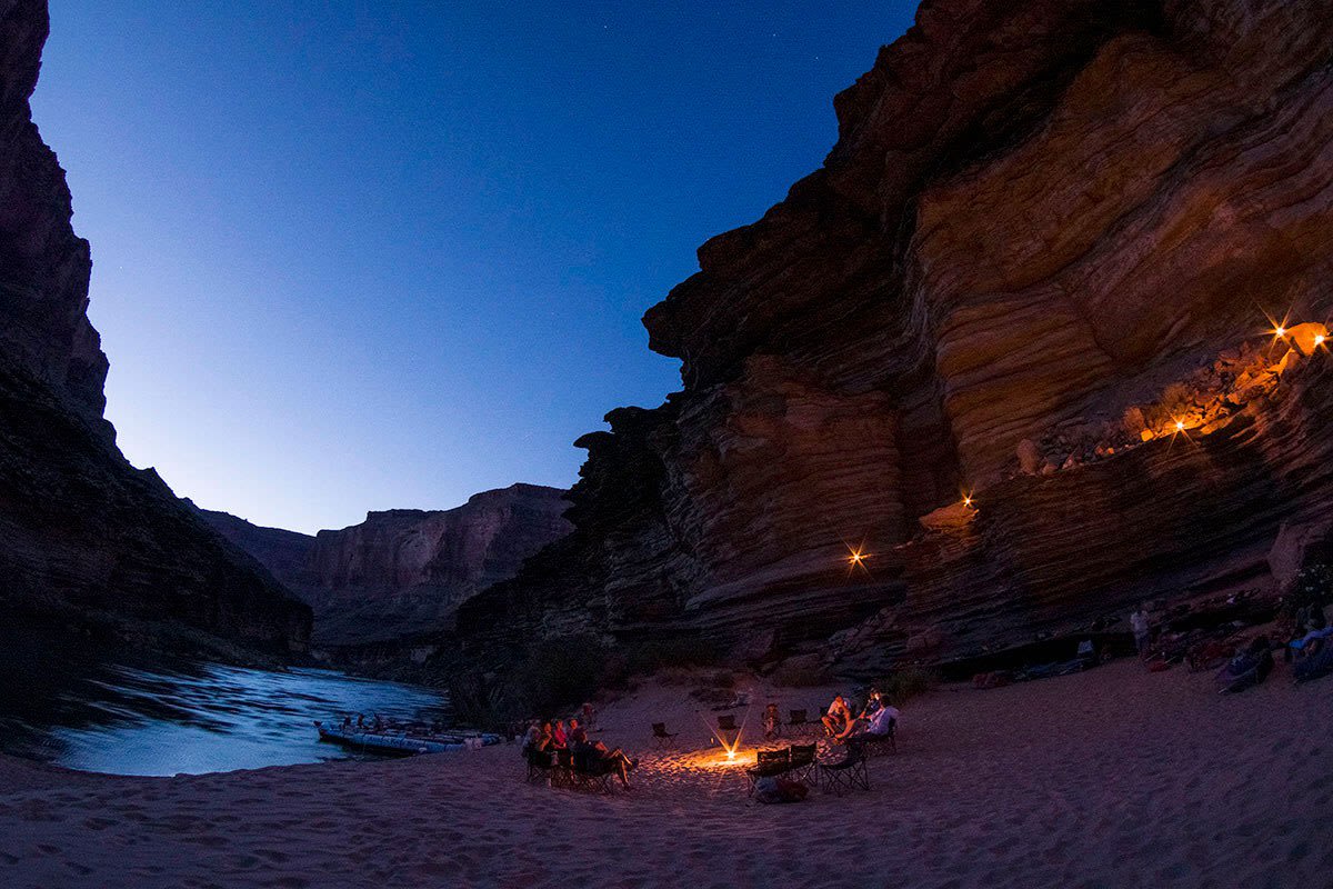 After a day of white-water rafting on the Colorado River, rafters relax beachside and prepare to camp for the night